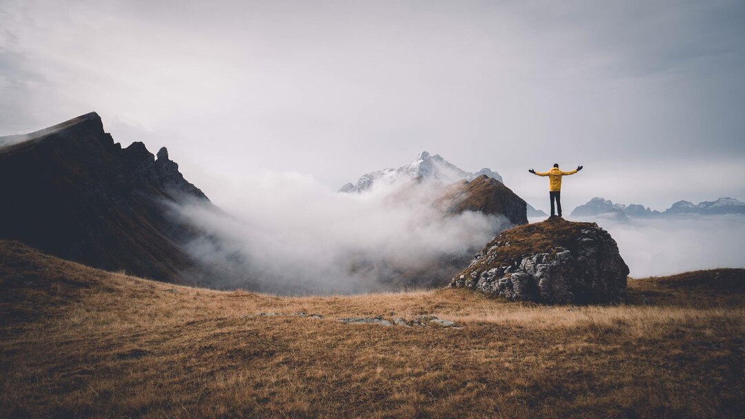 man-standing-rock-against-mountains-foggy-weather_1048944-13956285